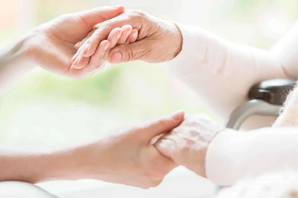 Geriatrics: Close-up of a young female chiropractor and a senior lady holding hands.